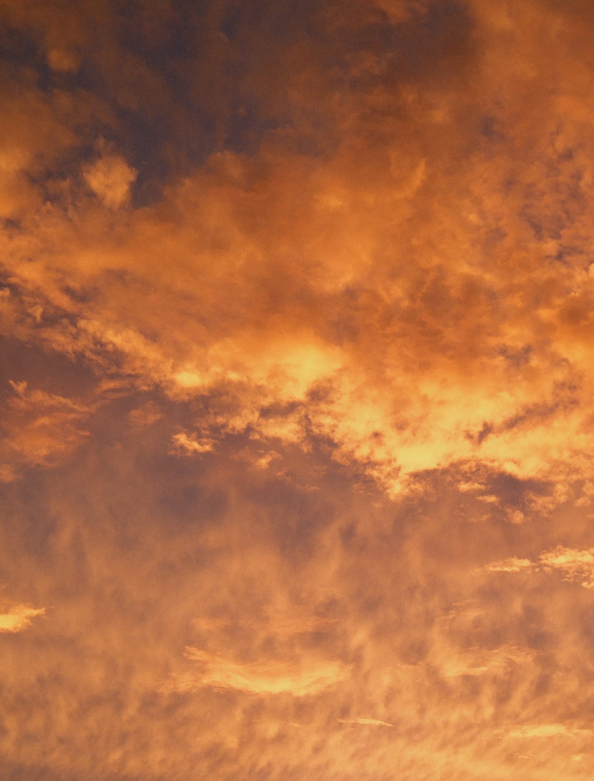 Vertical frame of textured amber and gold sunset clouds, no ground.
